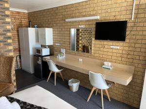 a kitchen with a counter with two chairs and a television at Squatters Homestead Motel in Casino