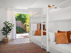 una camera con letto a castello bianco e cuscini arancioni di The Bach in Byron a Byron Bay