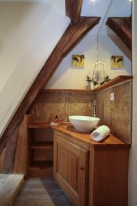 - une salle de bains mansardée pourvue d'un lavabo sur un comptoir en bois dans l'établissement Le Grenier du Chapitre, à Sarlat-la-Canéda