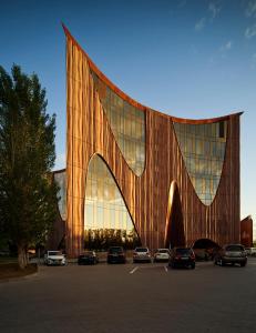 un gran edificio con coches estacionados en un estacionamiento en The Veil Hotel, en Astana