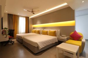 a hotel room with two beds and a yellow chair at ZIBE Salem By GRT Hotels in Salem