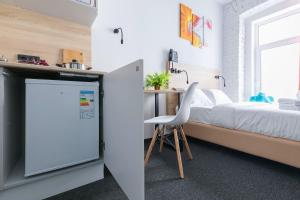 a bedroom with a bed and a refrigerator and a desk at IZZZI at Vladimirskaya in Saint Petersburg