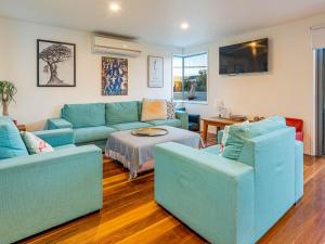 uma sala de estar com um sofá azul e duas cadeiras em Seashell on the Seashore em Cape Woolamai