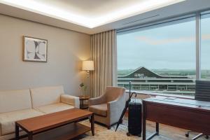 a living room with a couch and a desk and a window at LOTTE City Hotel Gimpo Airport in Seoul