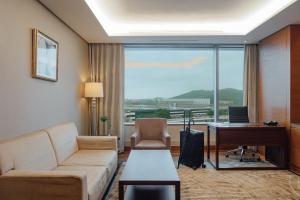 a living room with a couch and a desk and a computer at LOTTE City Hotel Gimpo Airport in Seoul