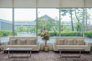 two white couches in a large room with windows at LOTTE City Hotel Gimpo Airport in Seoul