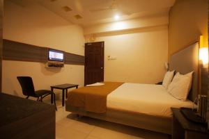 una camera d'albergo con letto, sedia e TV di P K Rresidency a Madurai