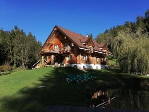 a large wooden house sitting on top of a lush green field at Chalet le Dorf in Nötsch