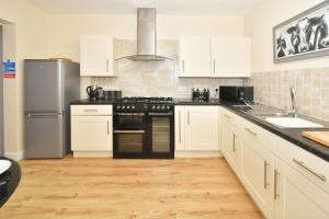 una cocina con armarios blancos y electrodomésticos negros en Alexandra Terrace by YourStays, en Crewe