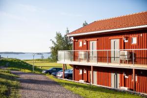a red house with a balcony and a car parked next to it at Skärgårdsbyn Hotell in Sankt Anna