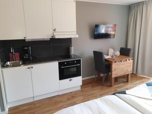 a kitchen with white cabinets and a wooden table at Skärgårdsbyn Hotell in Sankt Anna