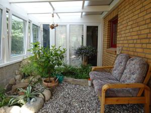 a porch with a chair and some plants at Kommod Stuv in Langstedt