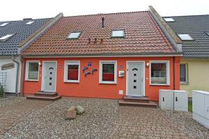 a red house with white doors and a tile roof at Ferienhaus Pruchten FDZ 311 in Pruchten