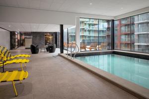 a swimming pool in a building with yellow chairs at Inntel Hotels Amsterdam Landmark in Amsterdam