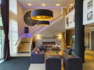 a living room with purple furniture and a staircase at HOTEL DU PARC Roissy Villepinte - Parc des Expositions in Roissy-en-France