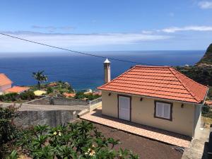 mały dom z czerwonym dachem i oceanem w obiekcie Panoramic Ocean View House w mieście Faial