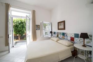 a white bedroom with a bed and a window at La Casetta di Sotto in Forio d'Ischia