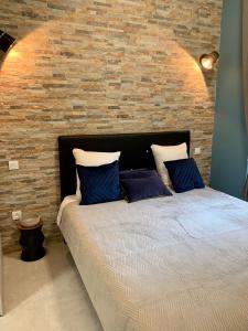 ein Bett mit blauen Kissen vor einer Ziegelwand in der Unterkunft LE 31 in Carcassonne