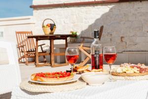una mesa con dos platos de comida y copas de vino en Tenuta Ulivi, en Putignano