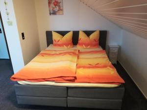 a bed with an orange comforter and pillows in a room at Apartment Preising in Willingen