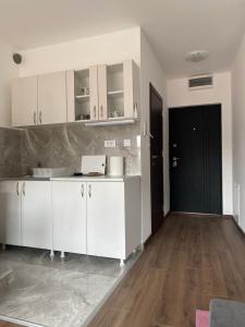a kitchen with white cabinets and a wooden floor at Dom apartmani in Kragujevac