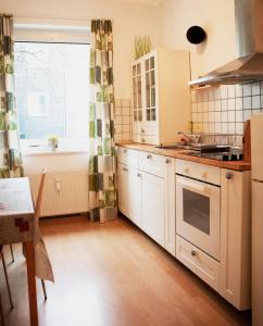 una cocina con armarios blancos y una ventana en Griffn Properties Flora, en Essen