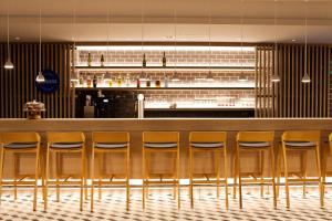 - un bar avec des tabourets en bois dans un restaurant dans l'établissement Holiday Inn Express - Recklinghausen, à Recklinghausen