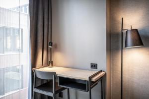 einen Schreibtisch in einem Zimmer mit einem Stuhl und einer Lampe in der Unterkunft Quality Hotel Hasle Linie in Oslo