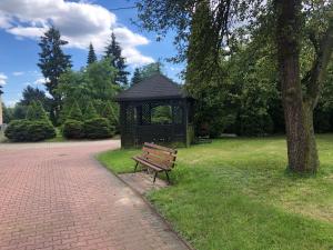 un banco de parque junto a un cenador en un parque en Hotel Zameczek, en Radomsko