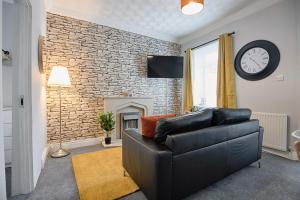 sala de estar con sofá y reloj en una pared de ladrillo en Crymlyn Accommodation - TV in Every Bedroom! en Swansea