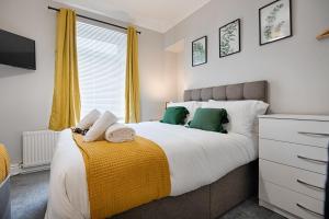 1 dormitorio con 1 cama grande con almohadas verdes en Crymlyn Accommodation - TV in Every Bedroom! en Swansea