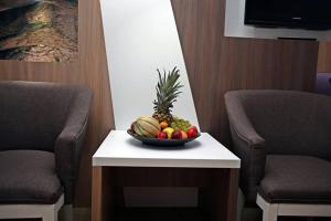 - un bol de fruits sur une table avec 2 chaises dans l'établissement Hotel Herceg, à Međugorje