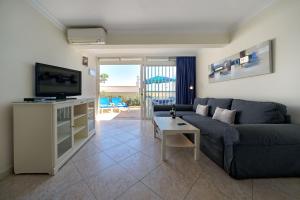 Una sala de estar con un sofá, un televisor y una mesa. en Ocean view apartments Las Flores I, en San Agustín