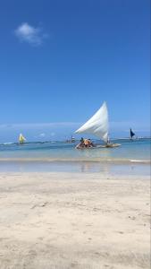 a group of people laying on the beach with a sail boat at Suítes Cavalo Marinho in Porto De Galinhas