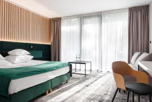 um quarto de hotel com uma cama, uma mesa e cadeiras em SZUMY PARK Hotel & Restaurant em Susiec