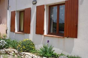 a house with wooden windows and flowers in front of it at La Tour Fondue Appartement vue mer Grand T2 face a Porquerolles Drap serviette non fournis in Hyères