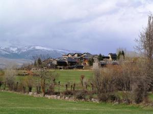 a group of houses in a field with mountains in the background at Cal Pedrals II in Urus