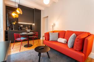 uma sala de estar com um sofá laranja e uma mesa em FLH Viola Market Studios no Funchal