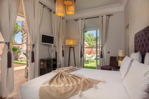 a bedroom with a large white bed and a television at Superbe Villa Y - Calme & sureté - Piscine privée & gouvernante in Marrakech +28 photos