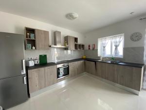 uma cozinha com armários de madeira e um frigorífico de aço inoxidável em Sunshine Apartments Mellieha - modern three bedroom apartment - Apt No 1 em Mellieħa
