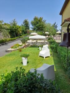 a garden with white chairs and a table and umbrella at B&B BOUTIQUE DI CHARME "ETNA-RELAX-NATURA" in Zafferana Etnea