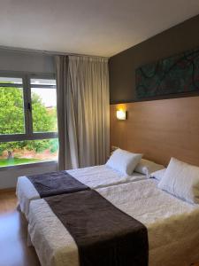 a hotel room with two beds and a window at Hotel Villa de los Arcos in Los Arcos