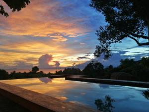 una piscina con una puesta de sol en el fondo en Nakabalo Guesthouse & Restaurant, en Siquijor