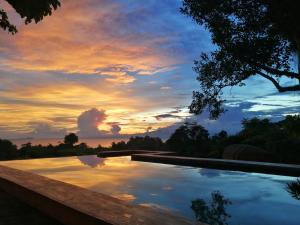 a pool with a sunset in the background at Nakabalo Guesthouse & Restaurant in Siquijor