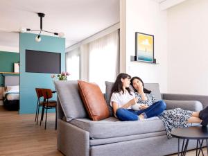 zwei Frauen auf einer Couch im Wohnzimmer in der Unterkunft Aparthotel Adagio Annecy Centre in Annecy