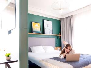 a little girl laying on a bed with a laptop at Aparthotel Adagio Annecy Centre in Annecy