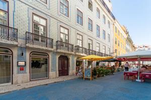 una calle con mesas y sombrillas frente a un edificio en Baixa Charming Apartment, en Lisboa