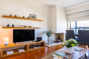 ein Wohnzimmer mit einem TV auf einem Holztisch in der Unterkunft Foz Premium Retreat in Porto