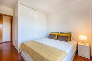ein Schlafzimmer mit einem großen weißen Bett mit gelben Kissen in der Unterkunft Foz Premium Retreat in Porto
