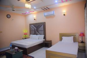 a bedroom with two beds and a table with lamps at Hotel Shaheen Continental Multan in Multan